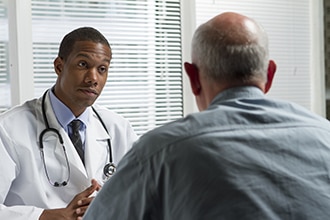 Doctor hablando con un paciente, ambos hombres.