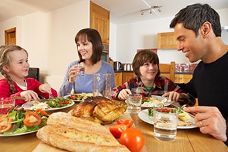 Fotografía de un padre y una madre con dos niños comiendo una cena saludable.