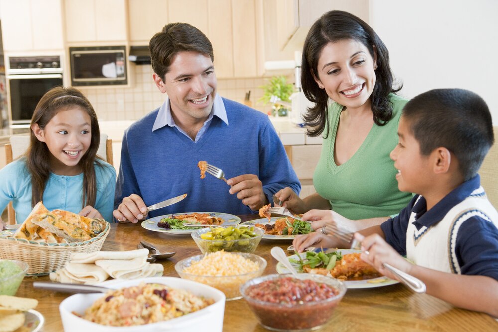 Two parents and two children eating dinner together.