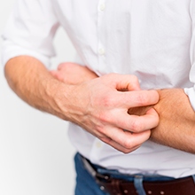 Man scratching itchy skin on his arm.
