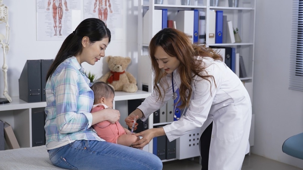 A health care professional giving a vaccine to an infant.