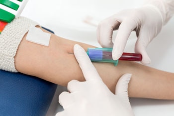 أخصائي رعاية صحية يجمع الدم من مريض.