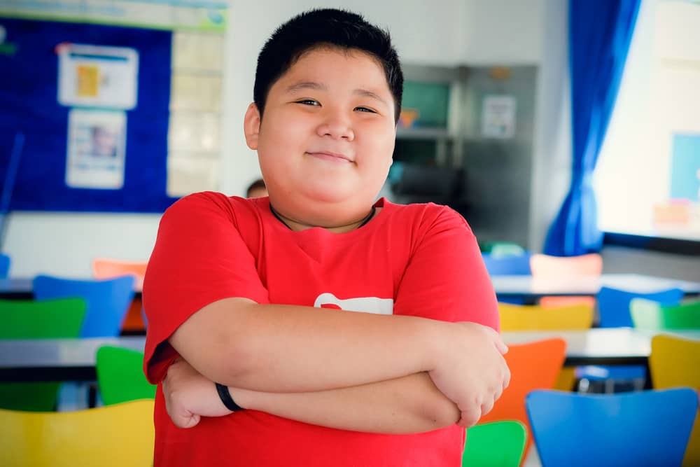 A boy with overweight or obesity in a classroom.