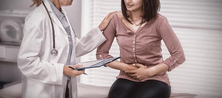 Woman with abdominal pain talking with a doctor.