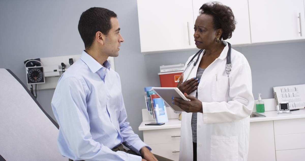 Doctora habla con un paciente en el consultorio médico.