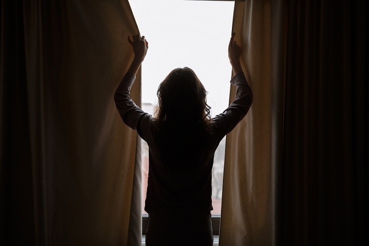 Woman closing window curtains