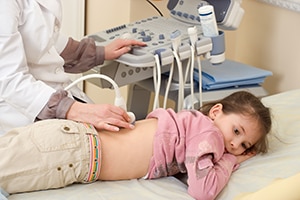 A child lies on her stomach while getting an ultrasound of her urinary tract.