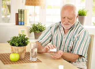 Un homme assis prenant un médicament oral avec de l'eau.