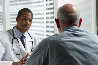 A health care professional listens to a male patient.