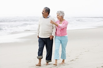 A man and a woman walk on a beach.