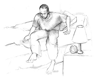 رجل يخرج من سريره ، بجانبه منضدة بجانب السرير مع مصباح.