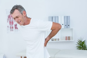 Photo of a man suffering from sharp pains in his lower back.