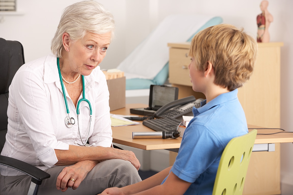 Doctor listens to a boy in her office.