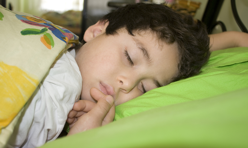 Boy sleeping under colorful blanket.