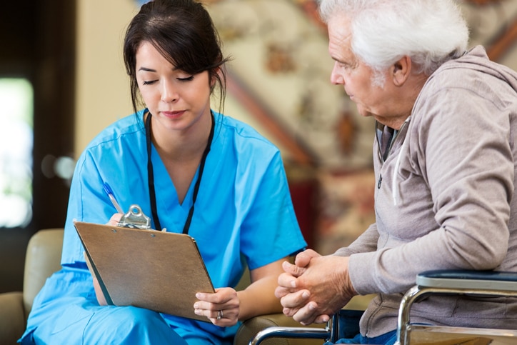 Health care professional sitting with a patient, filling out a medical form.