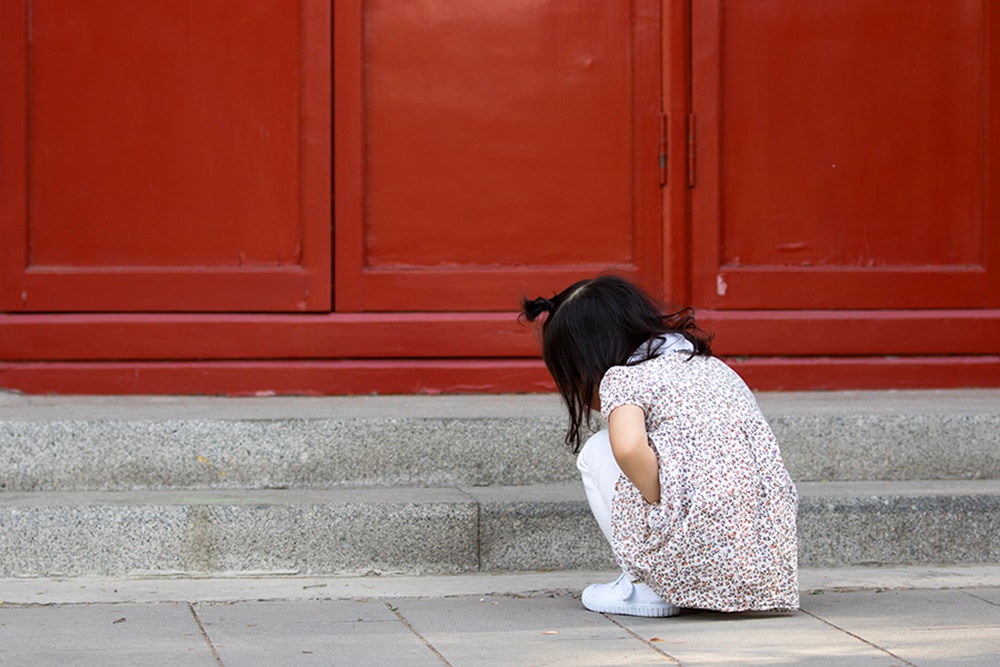 Young girl squatting to avoid leaking urine.