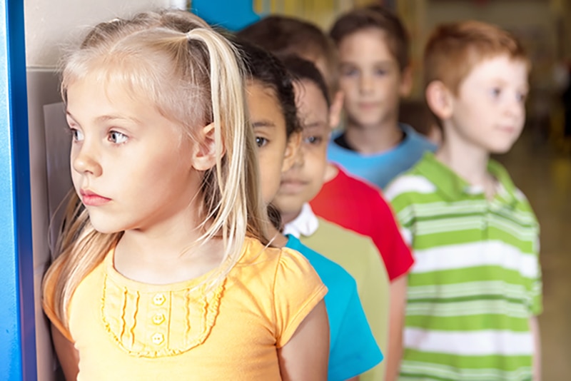 Young children lined up in a school hallway.