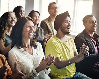 A group of adults applaud at a meeting.