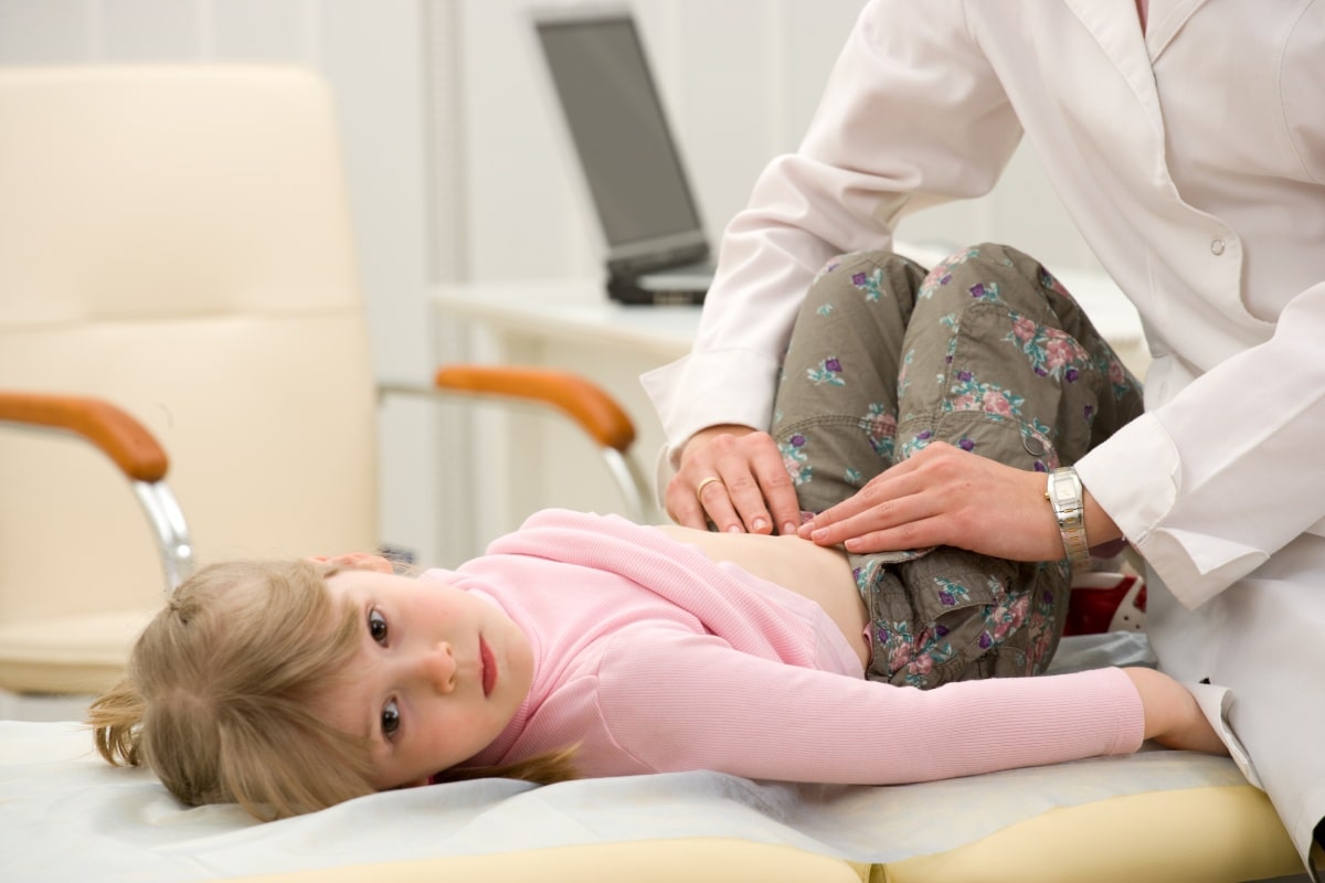 A doctor examining a young girl’s abdomen.