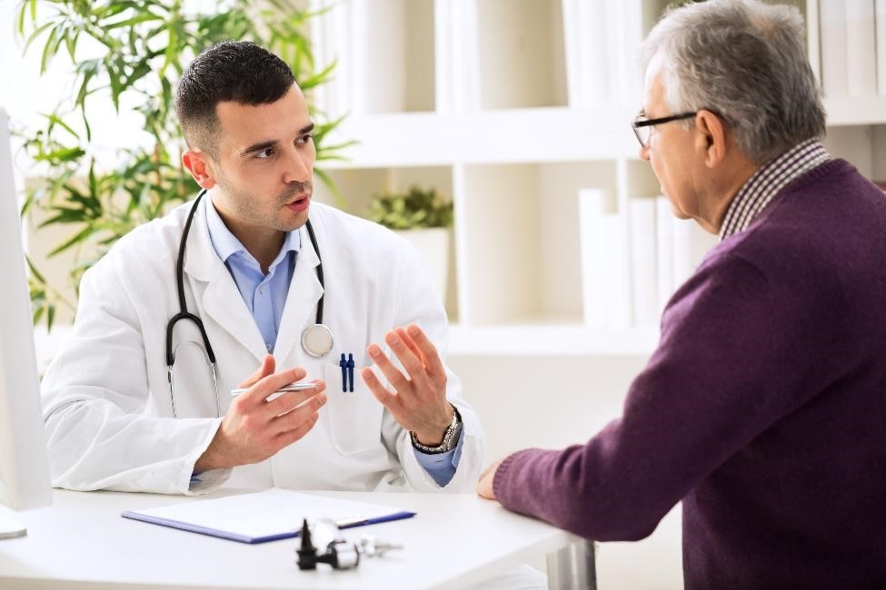 Health care professional talking with an older male patient.