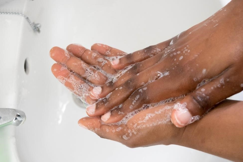 A woman washing her hands with soap and water. 