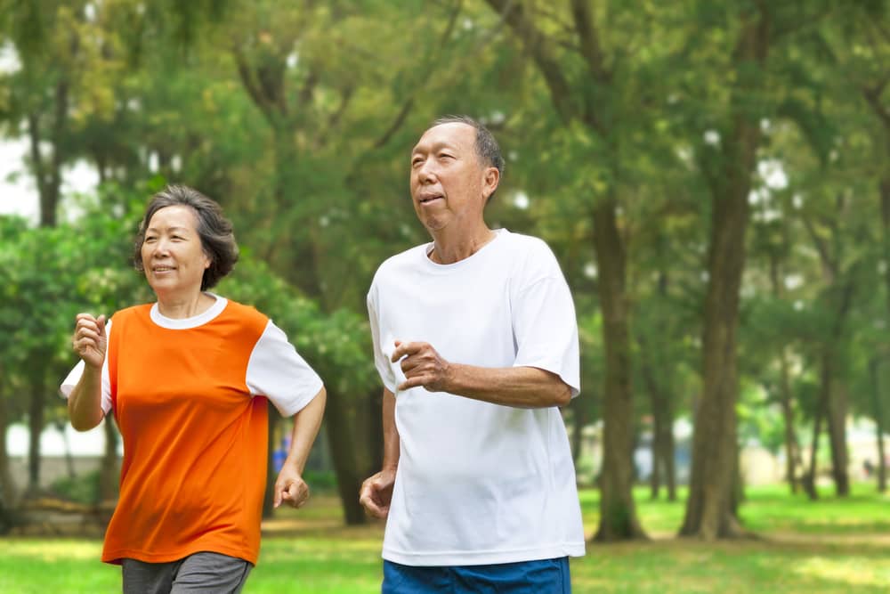 A woman and a man exercise in a park.