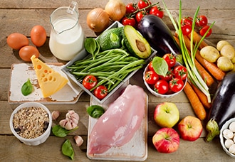 A variety of healthy, nutritious foods including vegetables, fruits, whole grains, cheese, eggs, milk, and chicken.