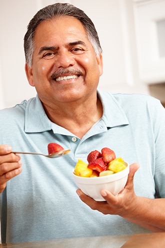Un hombre comiendo fruta fresca de un tazón.