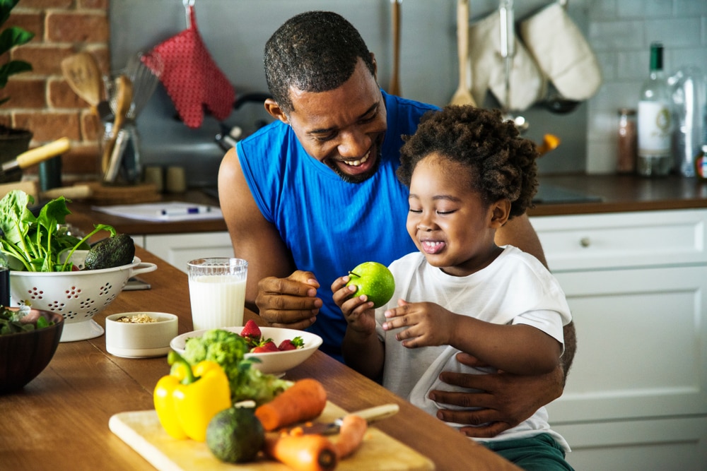 Father and child sitting in the kitchen eating healthy foods.