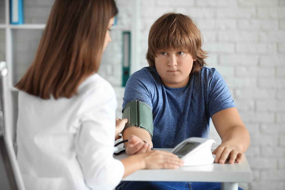 Una profesional de atención de salud controla la presión arterial de un niño utilizando un monitor de presión arterial.