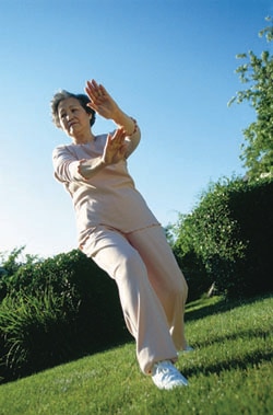 Older woman doing tai chi outside.