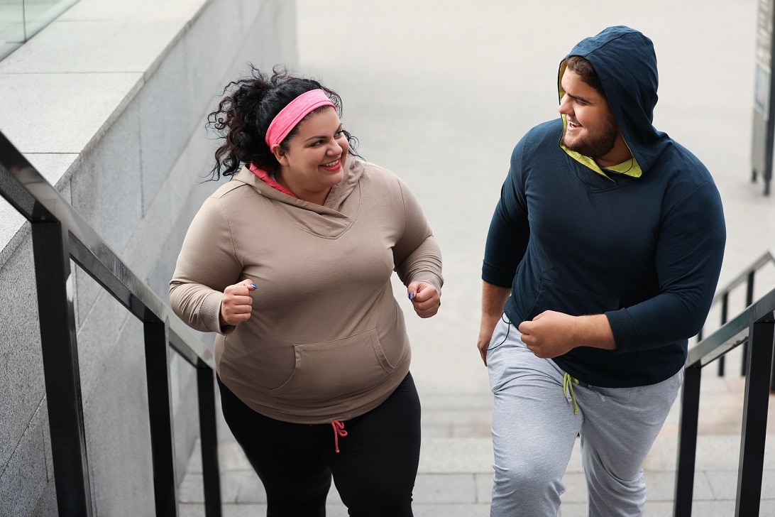 Two young people jogging up steps.