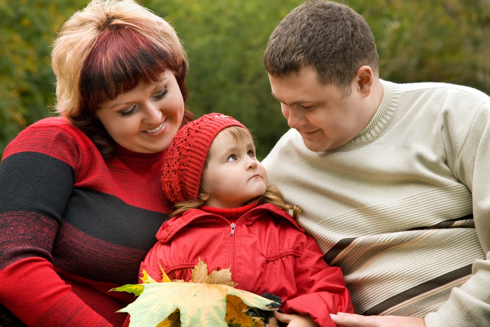 A man and woman who are overweight, sitting down, with a small child between them.