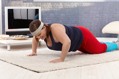 Woman doing a bent knee push-up in her home.