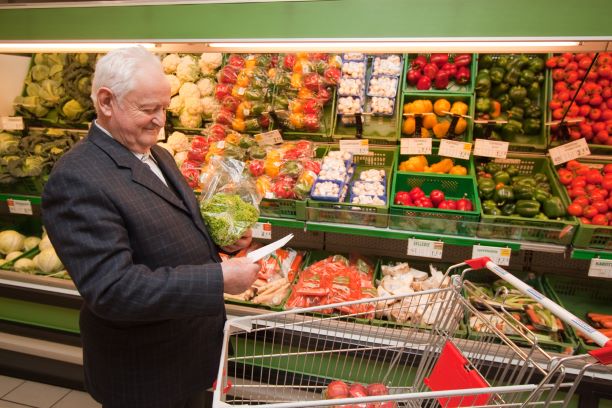 An older man shopping in a supermarket’s produce aisle.