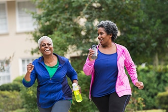 Two women walking outdoors carrying water bottles