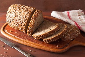 A sliced loaf of whole-grain bread on a cutting board.