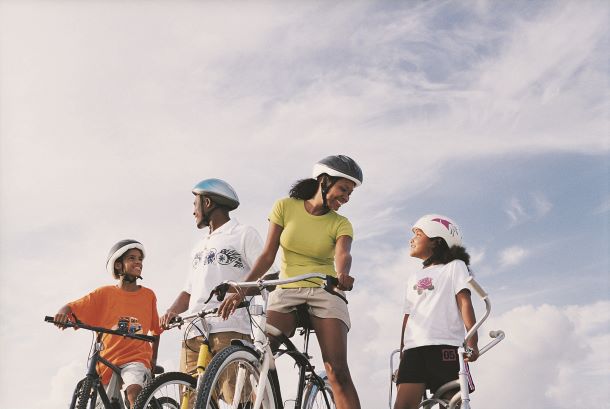 A family with two school-age children bikes together on a spring day.