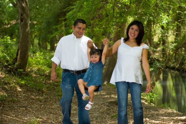 Una mujer embarazada camina por el bosque con su esposo y su hija pequeña.