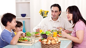 أسرة تجلس على طاولة العائلة وتتناول وجبة صحية.
