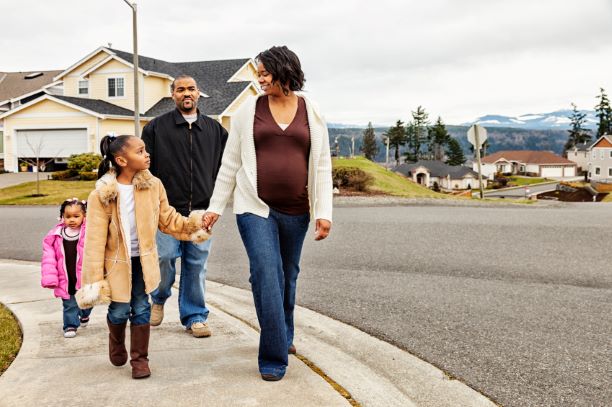 Pregnant woman taking a walk with her husband and two young children.