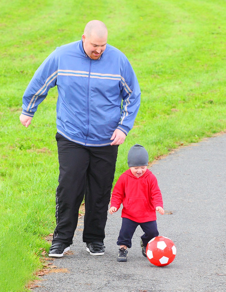 A man and child playing outdoors with a ball.