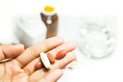 A hand holding several nutritional supplements.