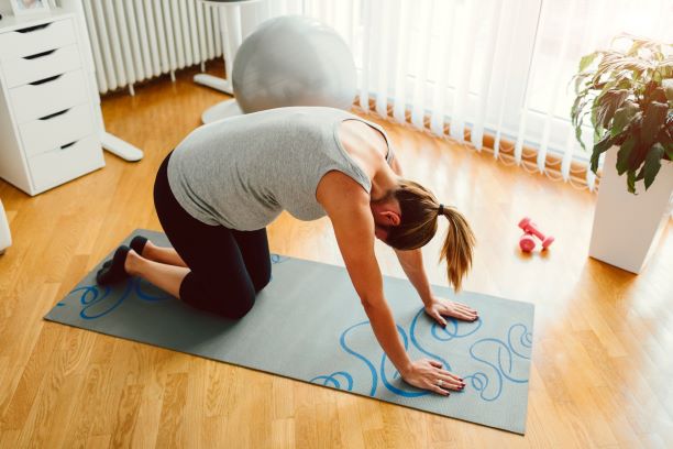 Pregnant woman does yoga pose on a yoga mat.