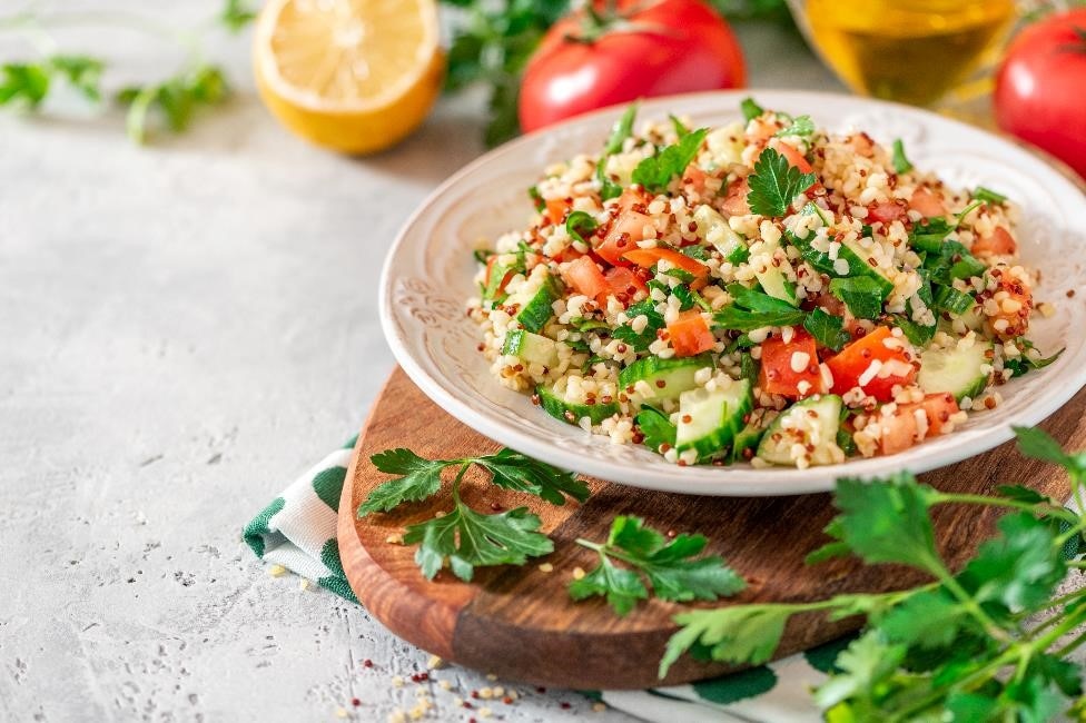 A plate of tabbouleh salad with bulgur, quinoa, tomato, cucumber, and parsley in a bowl.