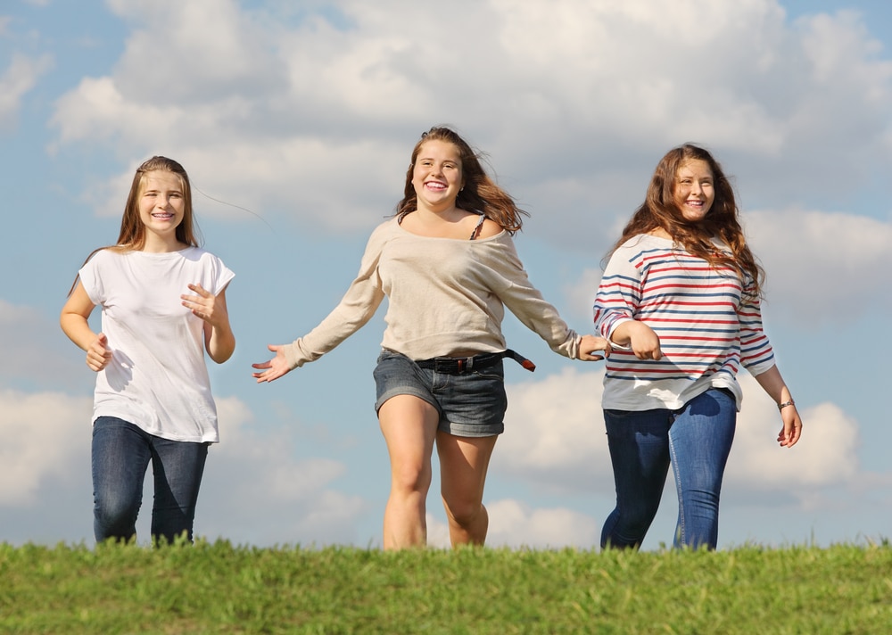Three teen girls walking together outdoors.