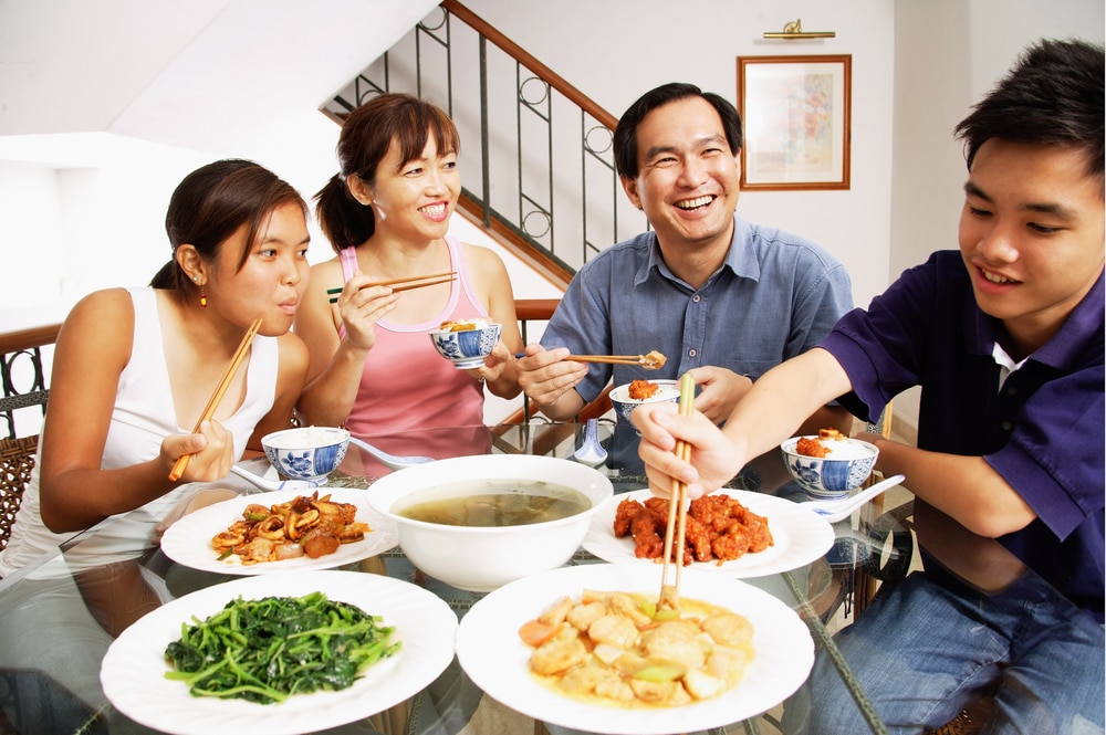 A family sitting at a kitchen table eating a healthy, home-cooked meal.