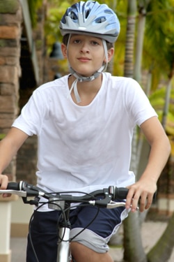 Photo of boy with bicycle helmet riding bicycle