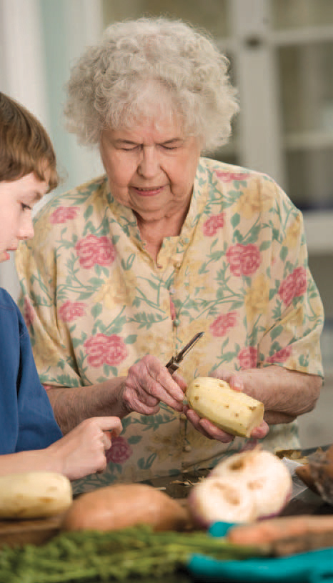 An older woman and a boy prepare food together.