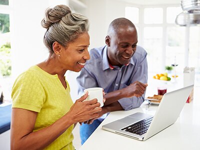 A couple reading something on a laptop screen while enjoying coffee